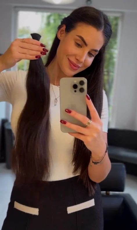 Długie, związane brązowe włosy trzymane przy lustrze, skup włosów Muse Hair